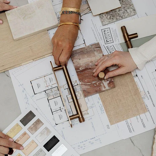 A team compares tile and color samples on an architectural board, using rulers and swatches to plan layout and finishes.