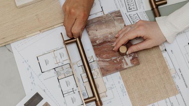A team compares tile and color samples on an architectural board, using rulers and swatches to plan layout and finishes.