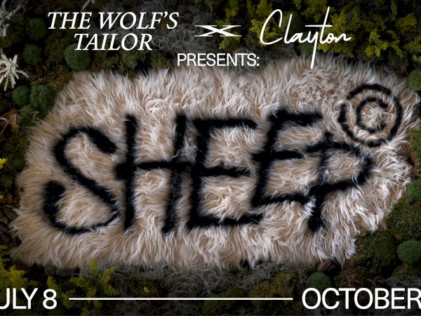 A furry wolf &ldquo;Clayton&rdquo; lies on moss in &ldquo;THE WOLF&rsquo;S TAILOR&rdquo; exhibit poster, dates July 8&ndash;October 4, presenting Clayton.