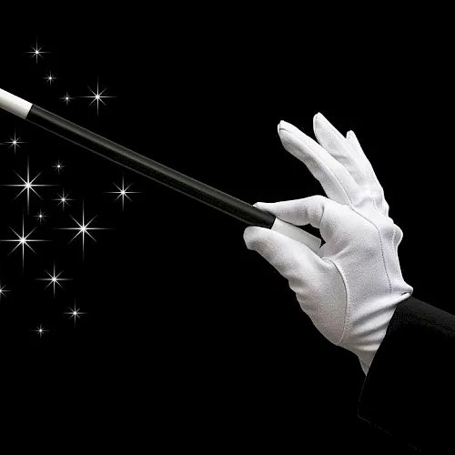 A gloved hand wields a wand over sparkling magic lights against a black background.