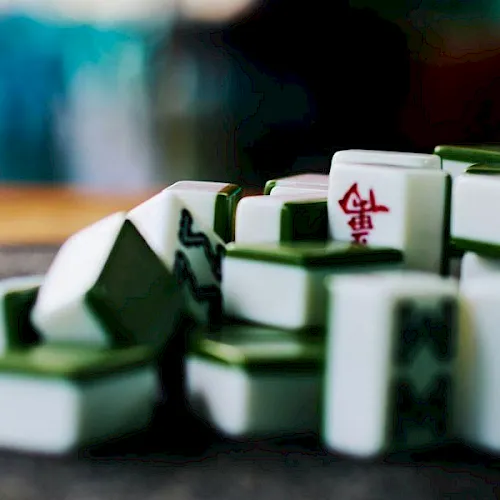 A close-up of domino-like Mahjong tiles scattered on a table, showing detailed faces and colors.