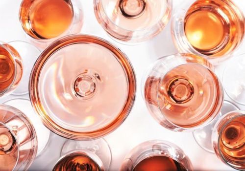 A top-down view of several small bottles filled with amber-orange liquid, arranged closely together on a bright white surface.