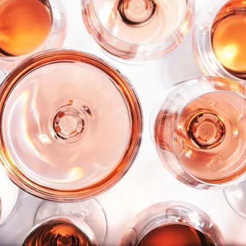 A top-down view of several small bottles filled with amber-orange liquid, arranged closely together on a bright white surface.