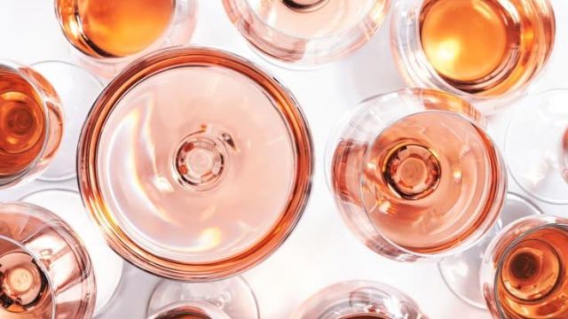 A top-down view of several small bottles filled with amber-orange liquid, arranged closely together on a bright white surface.