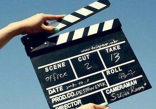 A person holds a black clapperboard movie slate with &ldquo;Scene,&rdquo; &ldquo;Take,&rdquo; and &ldquo;Roll&rdquo; markings against a blue sky, ending a filming moment.