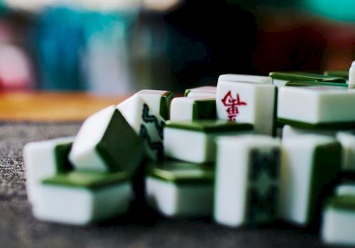 A close-up of Mahjong tiles scattered on a table, with a few marked backs in shallow depth of field.