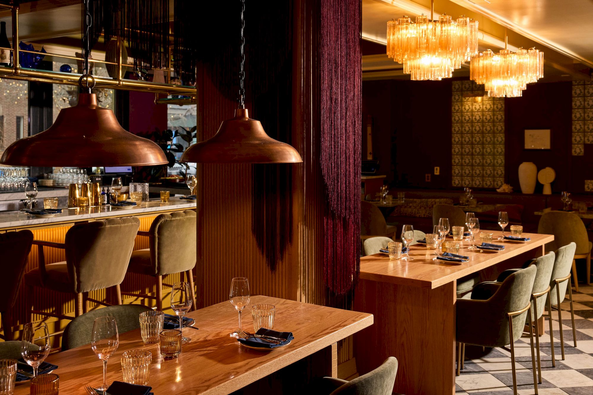 A stylish upscale restaurant with wooden tables, plush chairs, warm lighting, and modern pendant lamps creating an intimate dining vibe.