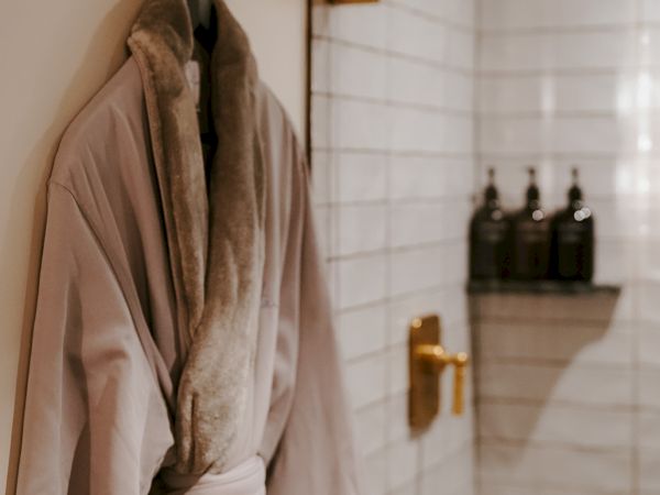 A plush robe hangs on a hook in a softly lit bathroom, a tranquil, spa-like moment.