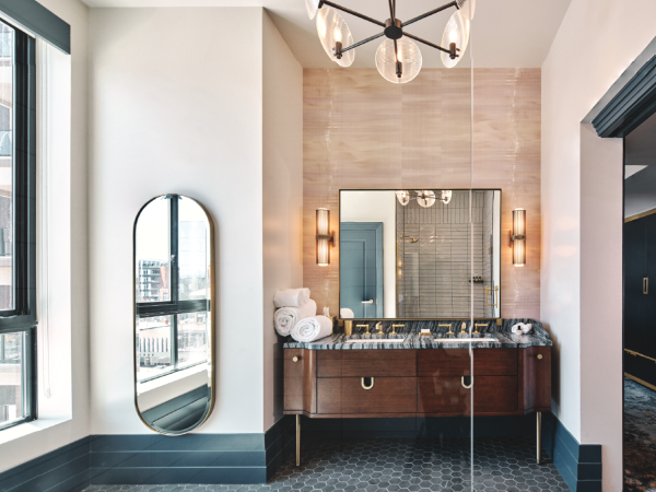 Elegant bathroom with a large mirror, stylish vanity, and modern light fixtures. Natural light streams through a window.