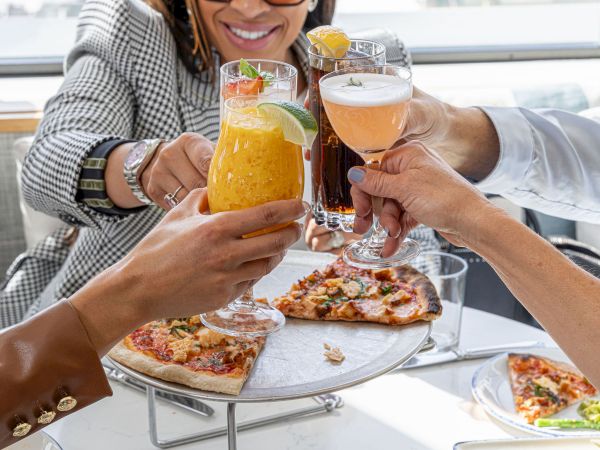 Cheers to good company, tasty pizza, and colorful drinks in a bright, cheerful brunch spot.