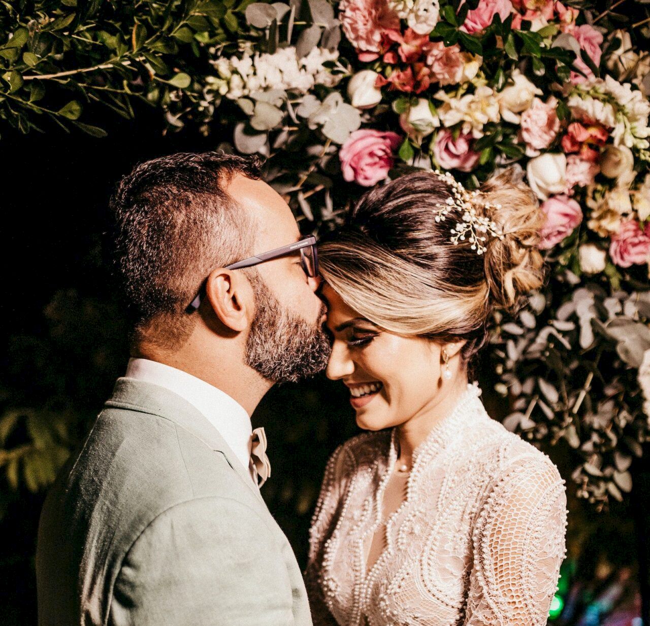 A couple is sharing an intimate moment at an event, surrounded by floral decorations.