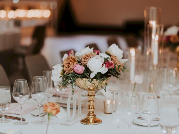 A formal table setting with an ornate flower centerpiece, glassware, and candles, perfect for a wedding or elegant dinner ceremony.