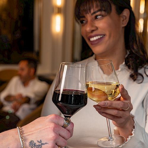 Two friends toast with wine glasses, smiling and enjoying a night out together.