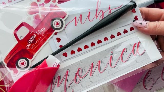 Valentine-themed gift set with pink cards, heart stickers, a small red toy car, and pink ribbon, all in clear packaging with names.