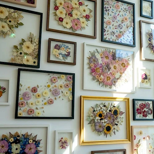 A wall filled with framed floral arrangements, many bouquets in pastel tones, arranged in varied frame sizes and styles.