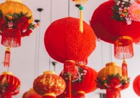 Colorful Chinese lanterns hanging from the ceiling, bright red and orange, with tassels and floral decorations, festive and decorative.