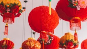 Colorful Chinese lanterns hanging from the ceiling, bright red and orange, with tassels and floral decorations, festive and decorative.