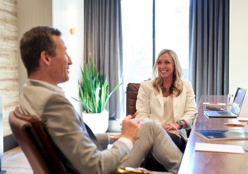 Two people in a business meeting smiling and talking in a modern office.