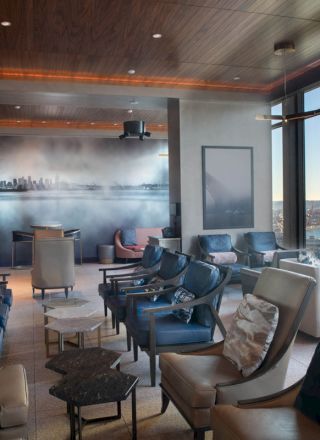 The image shows a modern, elegant lounge with plush seating, a large scenic window, and ambient lighting.