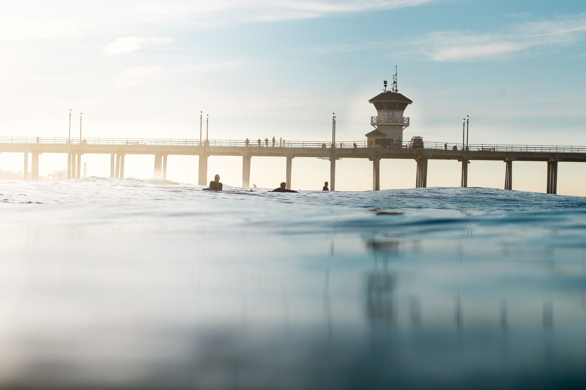 A scenic view of a pier extending over water with people walking, under a partly cloudy sky.